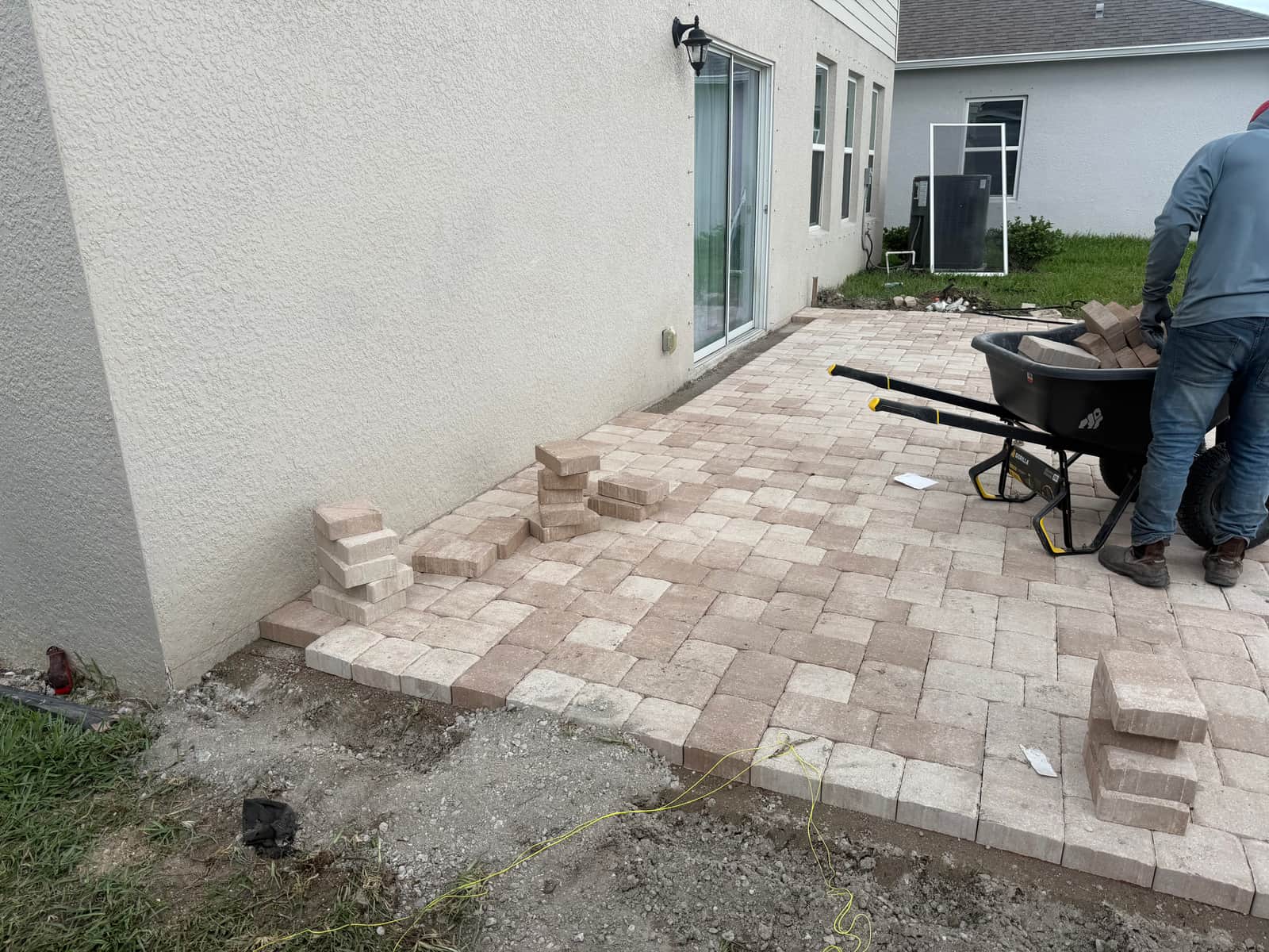 Crew laying pavers in a running-bond pattern, nearly covering the base